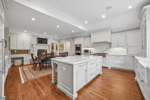 a kitchen with stainless steel appliances granite countertop a stove top oven a refrigerator a sink and a dining table with wooden floor