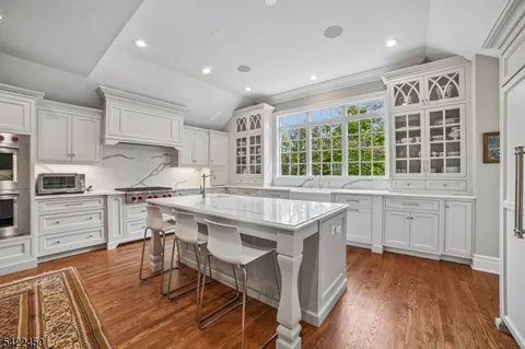 a kitchen with granite countertop a stove a sink dishwasher and a refrigerator with wooden floor