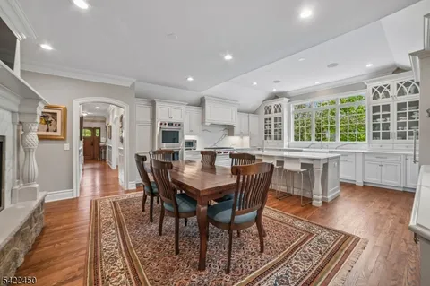 a dining hall with stainless steel appliances granite countertop a stove a couches table and chairs