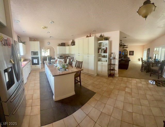 10561 Rancho Destino Road Las Vegas, NV 89183 - Photo 10 of 29 Kitchen featuring stainless steel refrigerator with ice dispenser, oven, white cabinetry, and light tile patterned floors