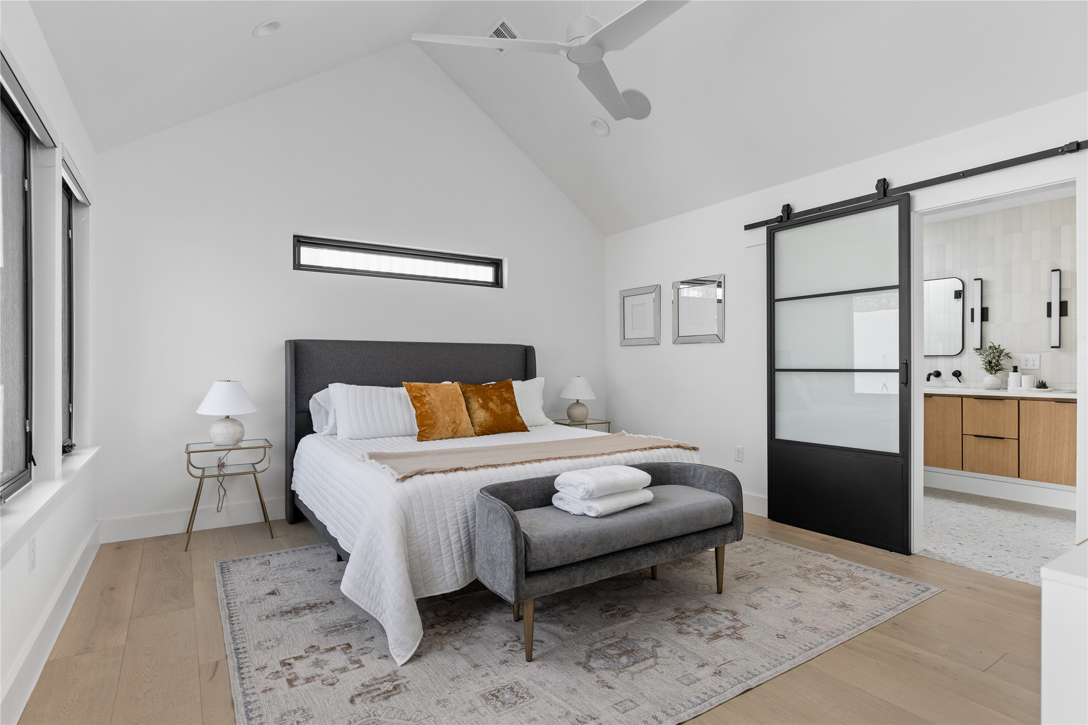108 Comal Street Austin, TX 78702 - Photo 13 of 40 Bedroom with a barn door, a ceiling fan, light wood-type flooring, a high ceiling, and connected bathroom