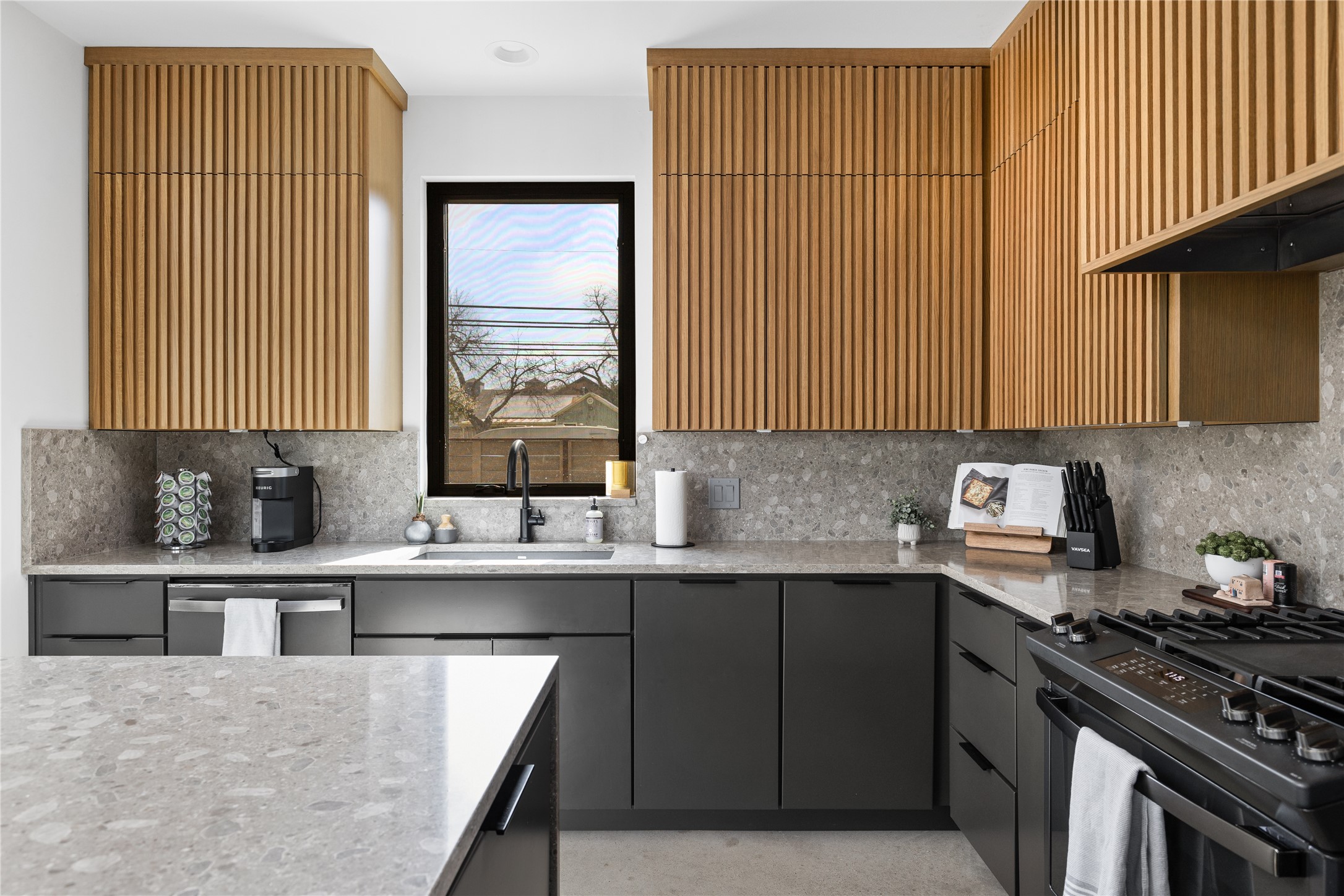 108 Comal Street Austin, TX 78702 - Photo 9 of 40 Kitchen featuring light stone countertops, black gas range, modern cabinets, stainless steel dishwasher, and gray cabinets