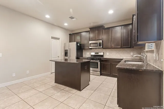 a kitchen with stainless steel appliances granite countertop a stove a sink and a refrigerator