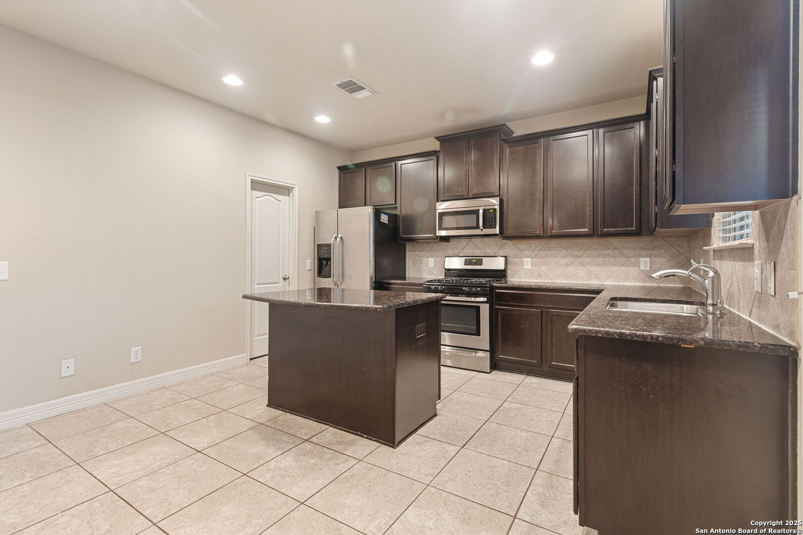 8806 Atwater Creek San Antonio, TX 78245 - Photo 3 of 16 a kitchen with stainless steel appliances granite countertop a stove a sink and a refrigerator