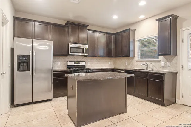 a kitchen with stainless steel appliances granite countertop a refrigerator stove and sink