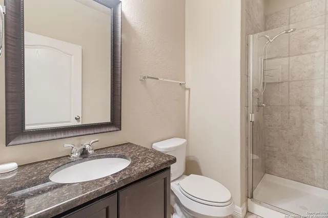 a bathroom with a granite countertop sink toilet a mirror and shower