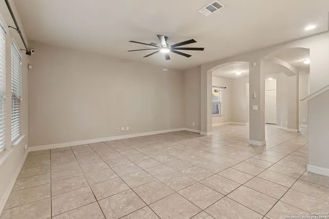 en empty room with white walls and ceiling fan