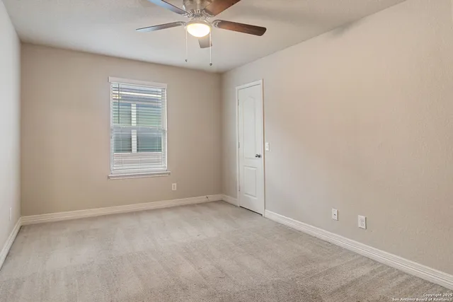 an empty room with a window and a fan