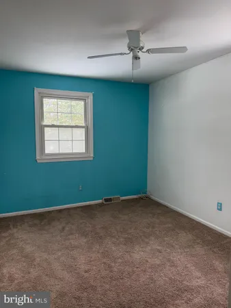 an empty room with a ceiling fan and windows