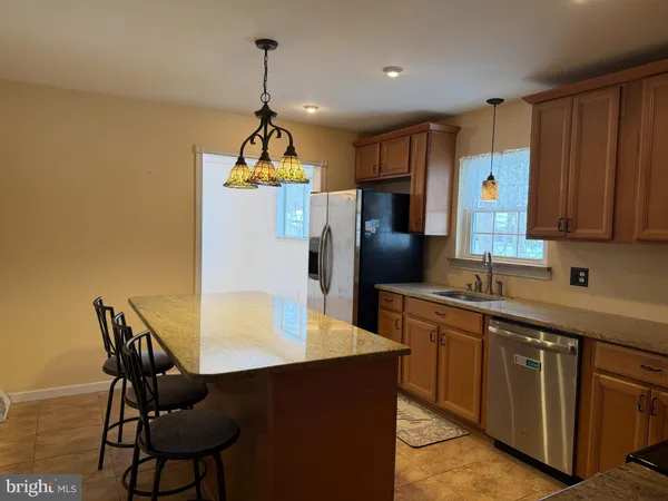 a kitchen with stainless steel appliances kitchen island a table chairs in it and wooden floors