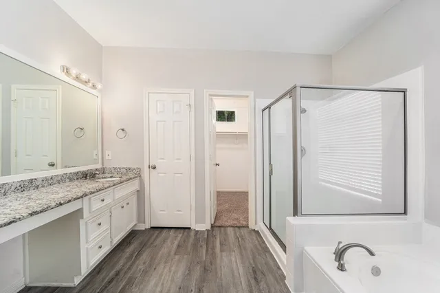 a spacious bathroom with a granite countertop sink mirror and a bathtub