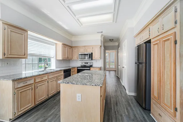 a kitchen with stainless steel appliances granite countertop a refrigerator a sink dishwasher a stove and white countertops with wooden floor