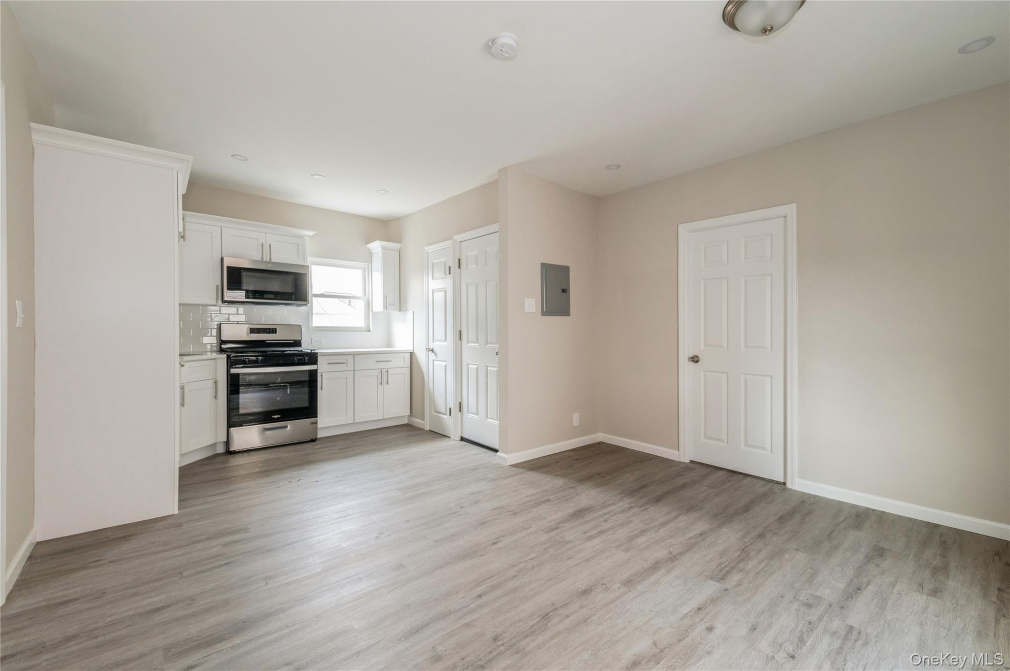 216-23 136th Road Queens, NY 11413 - Photo 16 of 28 Kitchen with appliances with stainless steel finishes, white cabinetry, light wood-style floors, decorative backsplash, and recessed lighting