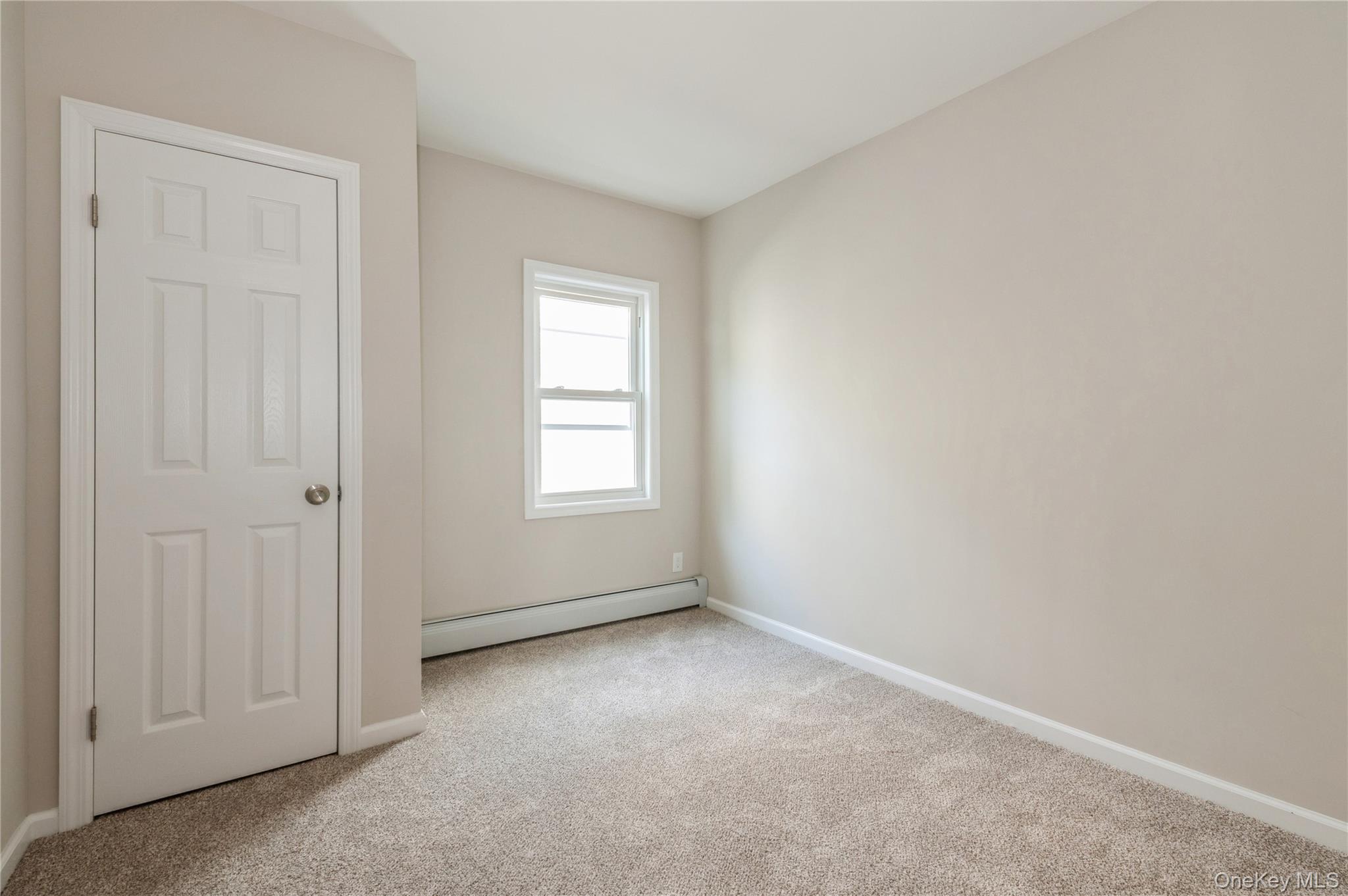 216-23 136th Road Queens, NY 11413 - Photo 23 of 28 Unfurnished bedroom featuring light carpet and baseboard heating