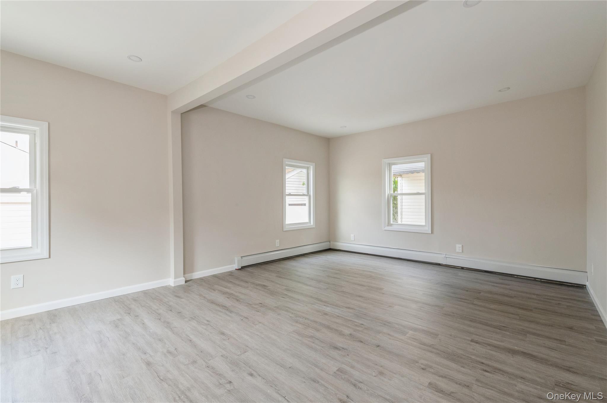 216-23 136th Road Queens, NY 11413 - Photo 10 of 28 Empty room featuring light wood-style floors, baseboard heating, and beamed ceiling