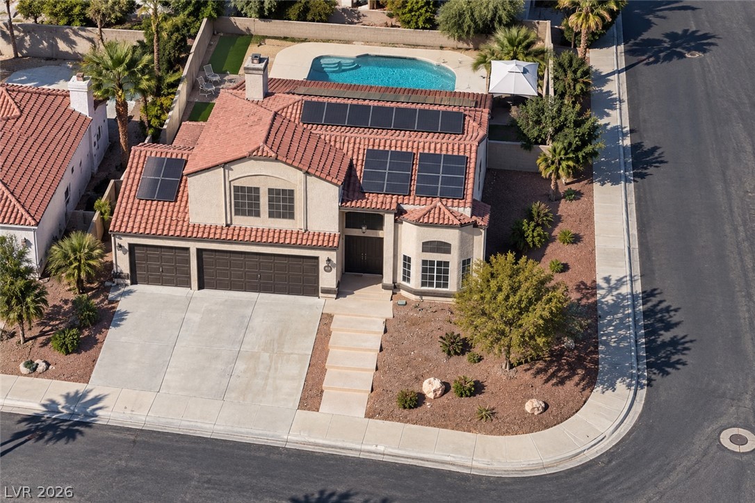 43 Bayridge Road Henderson, NV 89074 - Photo 3 of 47 An aerial perspective showcases a tile roof home featuring solar panels and a backyard pool.