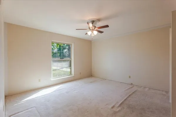 an empty room with windows and fan