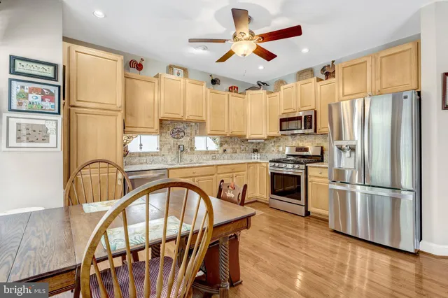 a kitchen with stainless steel appliances granite countertop a refrigerator a stove a sink dishwasher a dining table and chairs with wooden floor
