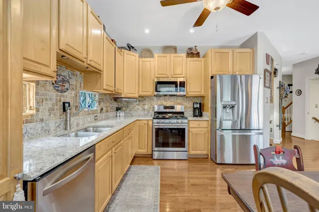 a kitchen with stainless steel appliances granite countertop a refrigerator a stove and a sink