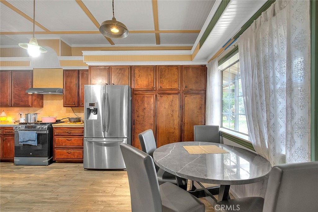 8529 Nielson Road Phelan, CA 92371 - Photo 10 of 44 a kitchen with stainless steel appliances kitchen island granite countertop a refrigerator a stove a sink dishwasher with a dining table and chairs