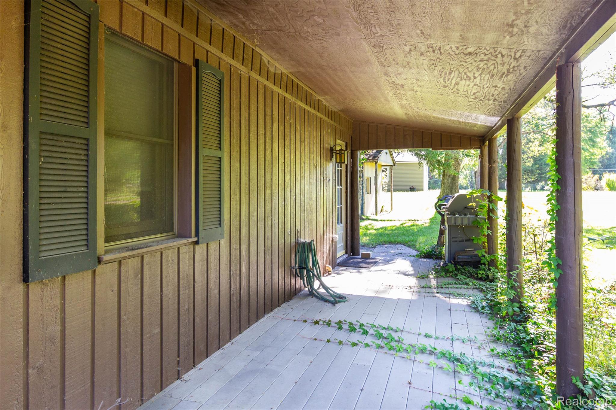 14044 Ridgemont Drive Gregory, MI 48137 - Photo 4 of 33 Covered porch with wood-finish siding, louvered shutters, and outdoor lighting fixture