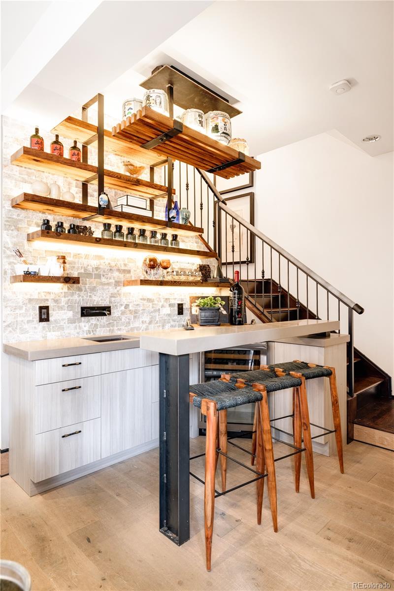 469 Cook Street Denver, CO 80206 - Photo 37 of 50 a kitchen with stainless steel appliances kitchen island a table chairs in it and wooden floors