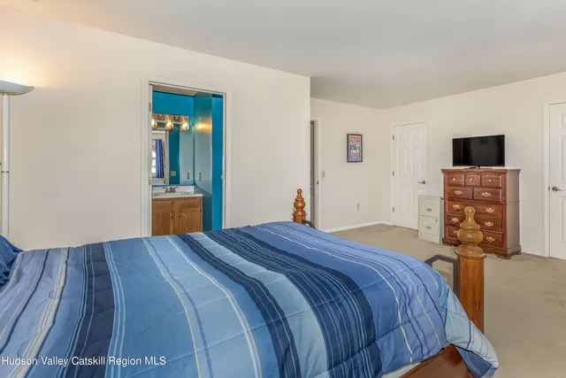 a bedroom with a bed and a dresser with wooden floor
