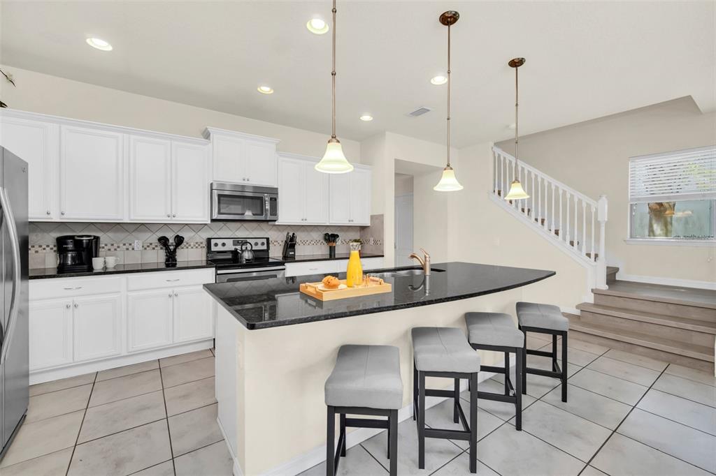 2070 Rome Drive Kissimmee, FL 34747 - Photo 11 of 57 a kitchen with stainless steel appliances granite countertop a sink a stove a refrigerator a microwave oven a stove with white cabinets