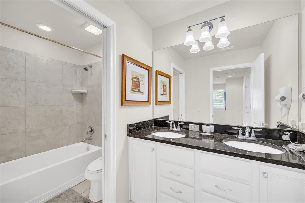 2070 Rome Drive Kissimmee, FL 34747 - Photo 44 of 57 a bathroom with a granite countertop sink a toilet a mirror a bathtub and shower