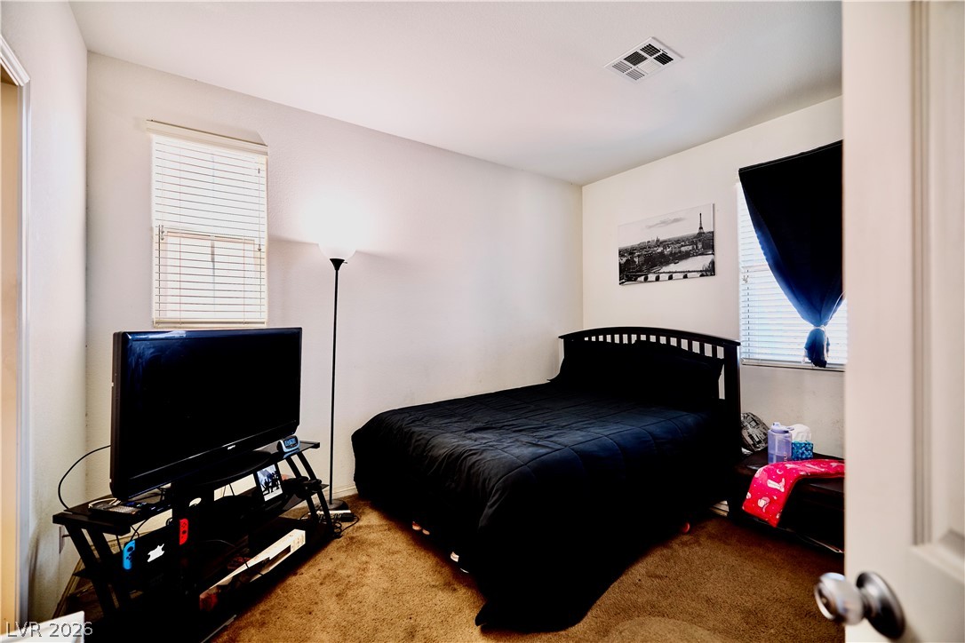 193 Tuscan Shadow Street Henderson, NV 89012 - Photo 15 of 27 This cozy downstairs bedroom features warm carpeting and ample natural light, creating a comfortable and inviting atmosphere.