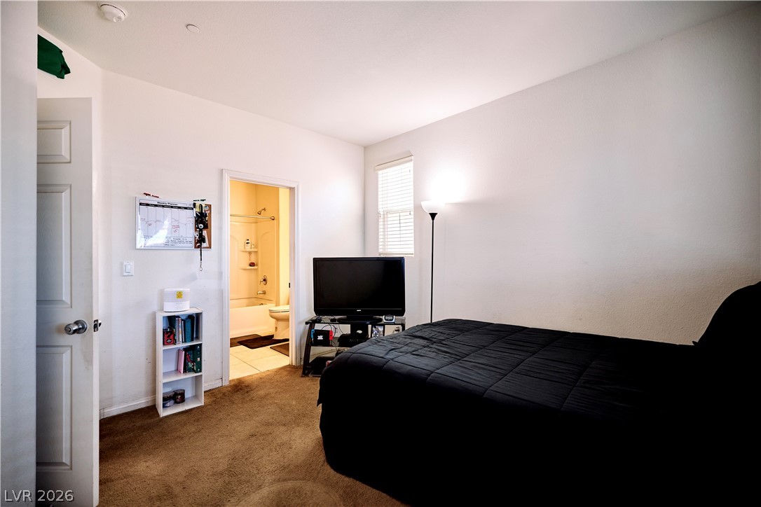 193 Tuscan Shadow Street Henderson, NV 89012 - Photo 16 of 27 This bedroom features warm carpet flooring and a private bathroom entrance, creating a comfortable personal retreat.