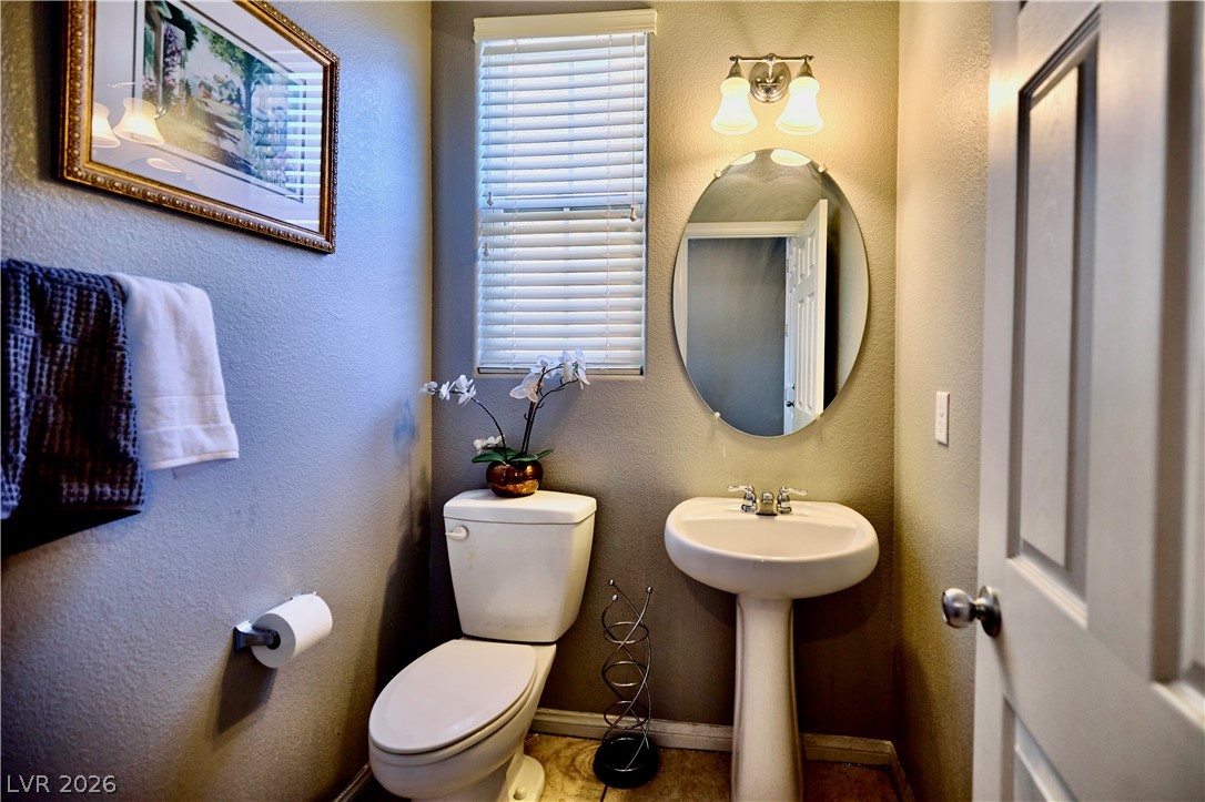 193 Tuscan Shadow Street Henderson, NV 89012 - Photo 6 of 27 This downstairs bathroom features a contemporary pedestal sink and toilet, accented by a window with blinds.