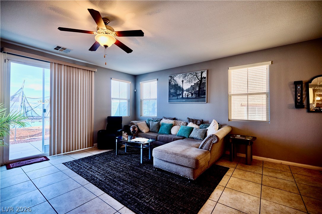 193 Tuscan Shadow Street Henderson, NV 89012 - Photo 9 of 27 This inviting living space features tiled floors, a ceiling fan, and sliding doors opening to an outdoor area.