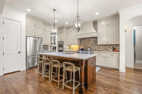a kitchen with stainless steel appliances granite countertop a wooden floor and white cabinets