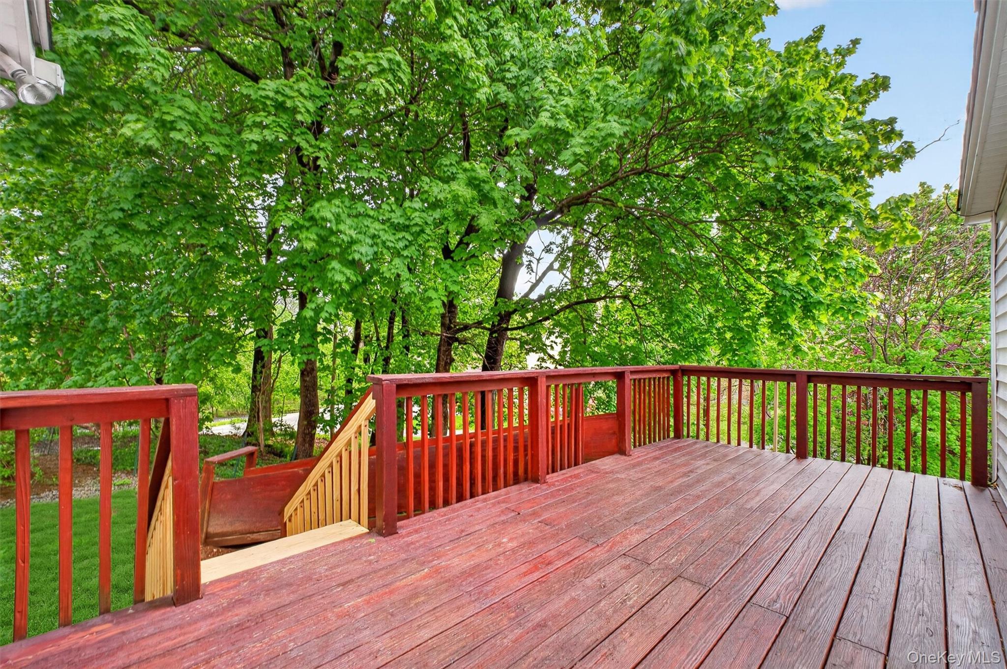 121 Old Glenham Road Fishkill, NY 12524 - Photo 40 of 50 Spacious outdoor deck with wood flooring and matching railings, featuring a verdant tree canopy backdrop and integrated stairs.