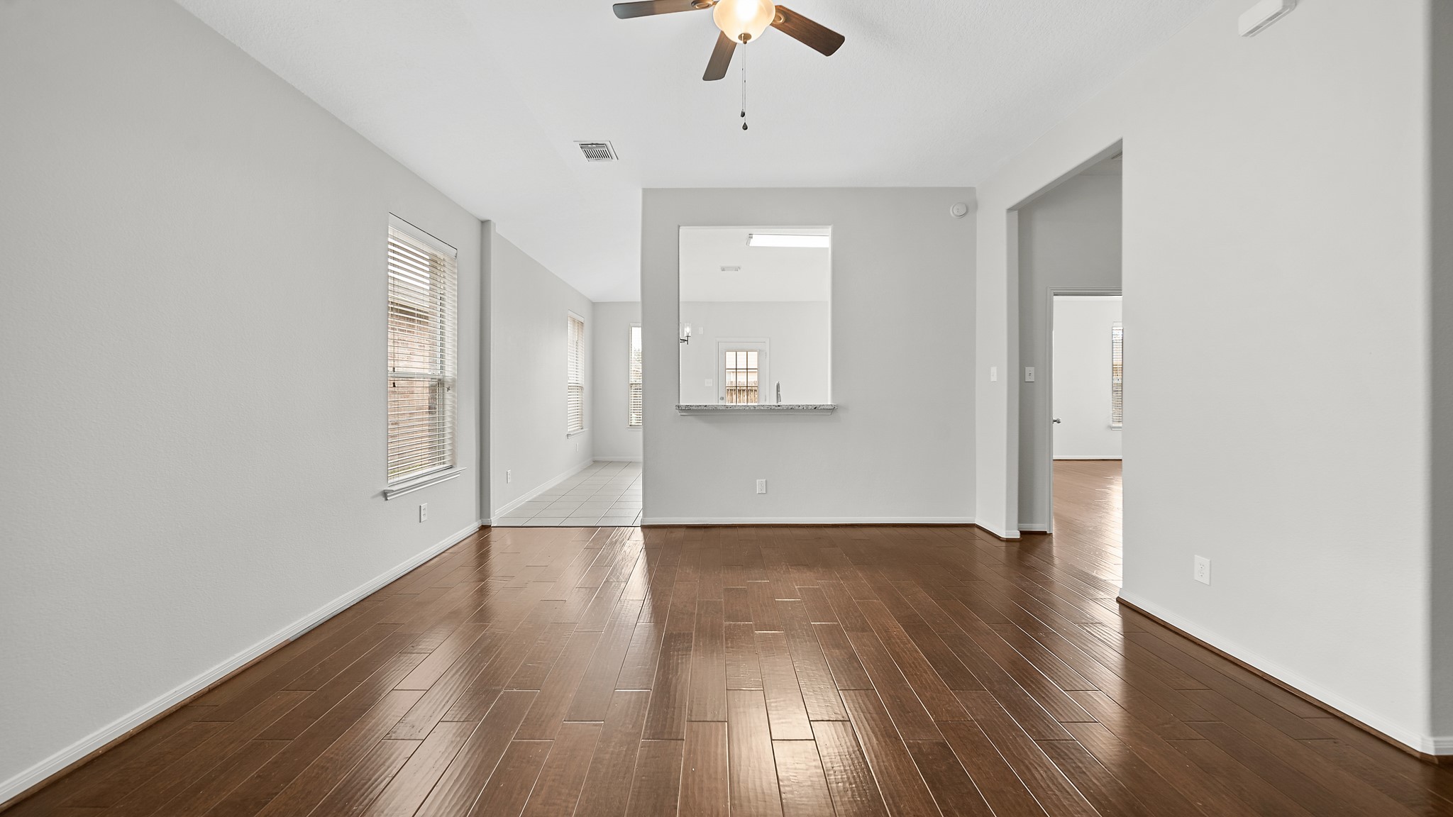 15710 Flagstone Walk Way Houston, TX 77049 - Photo 4 of 27 an empty room with wooden floor chandelier fan and windows