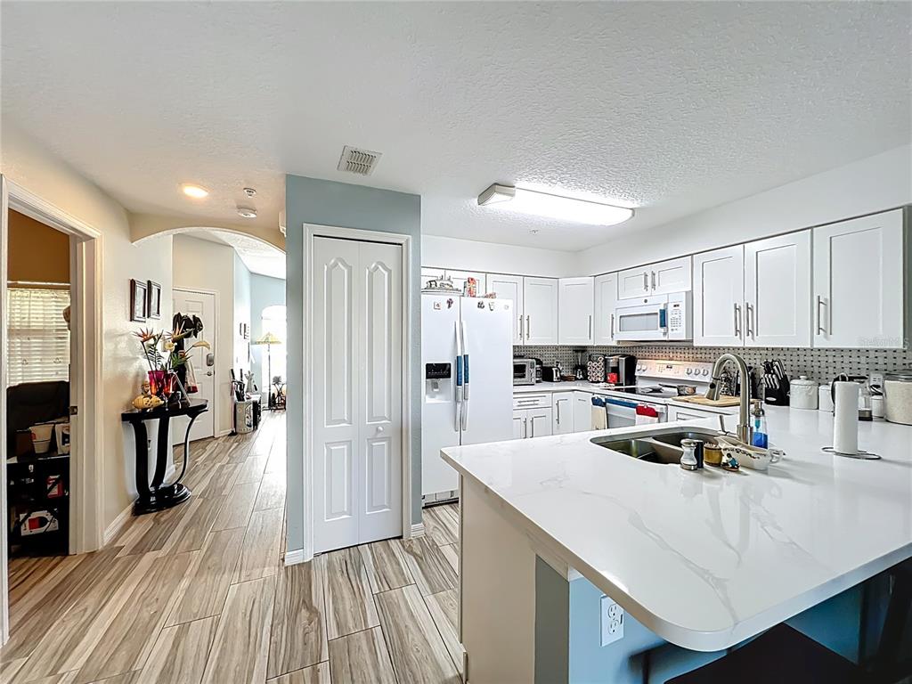 676 Sandy Neck Lane, Unit 101 Altamonte Springs, FL 32714 - Photo 6 of 24 a kitchen with a refrigerator a stove and white cabinets with wooden floor