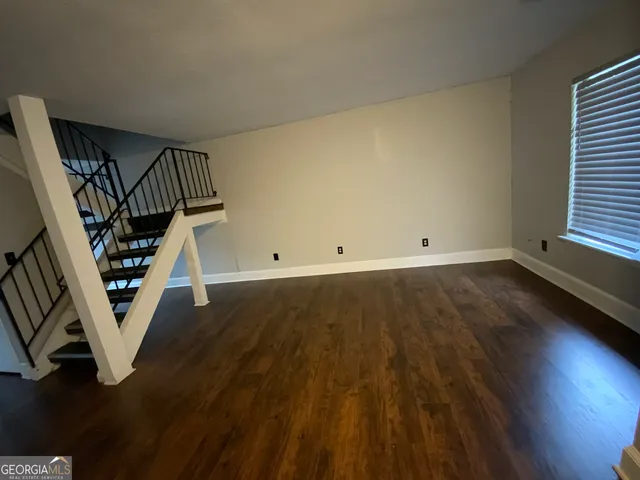 an empty room with wooden floor and staircase