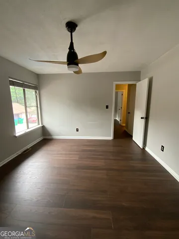 a view of an empty room with window and wooden floor