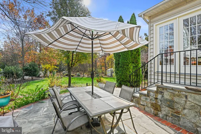 a view of a patio with table and chairs under an umbrella with a small yard