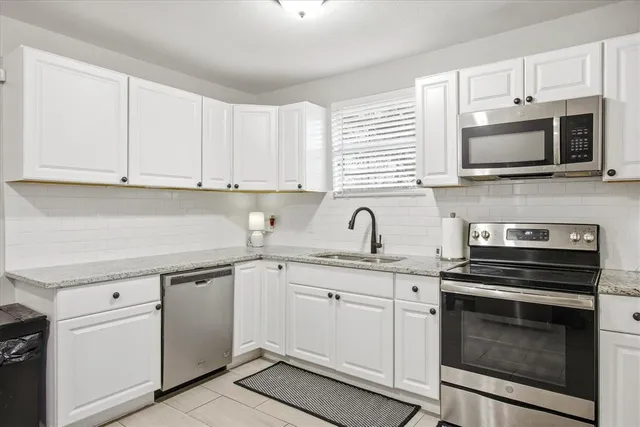 a kitchen with white cabinets stainless steel appliances and sink