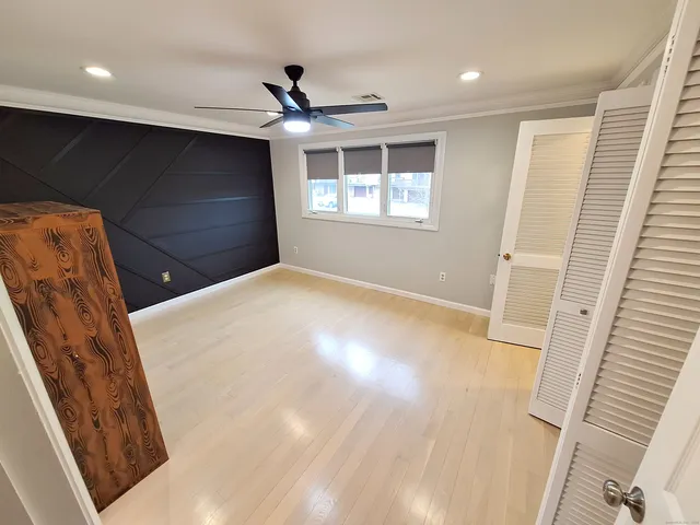 a view of empty room with wooden floor and fan