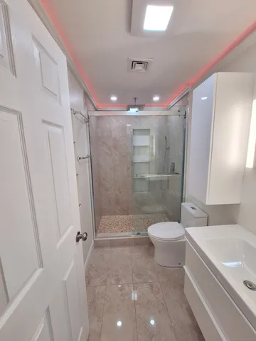 a bathroom with a granite countertop sink a toilet and shower