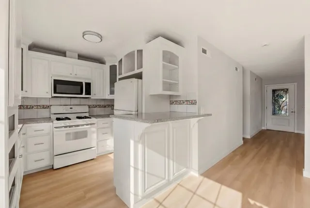 a kitchen with stainless steel appliances white cabinets and white appliances