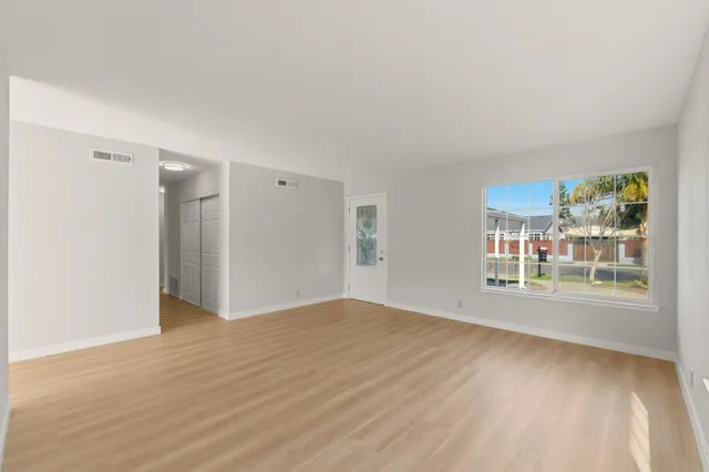 a view of an empty room with a window and wooden floor