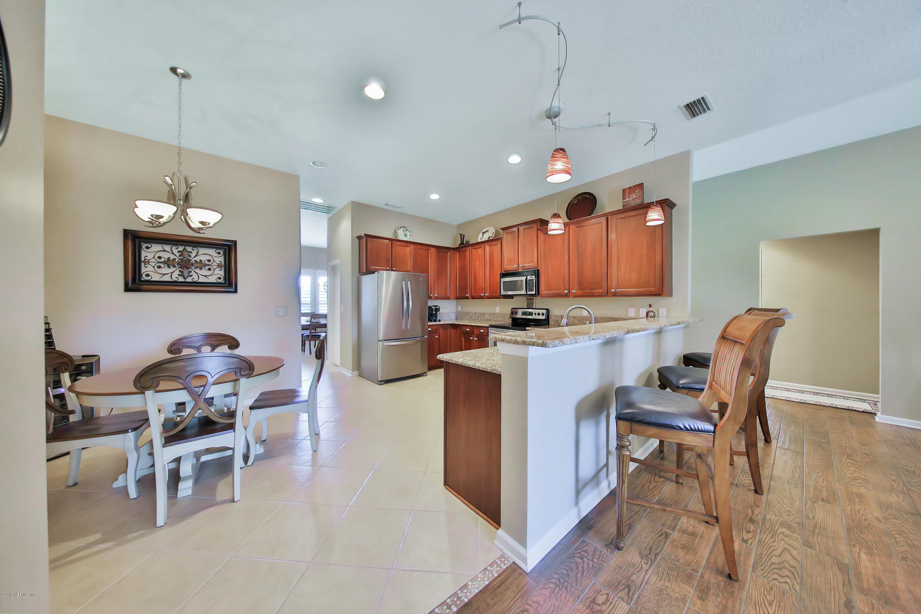 712 Porta Rosa Circle St. Augustine, FL 32092 - Photo 9 of 34 a kitchen with stainless steel appliances kitchen island granite countertop a dining table chairs and a refrigerator