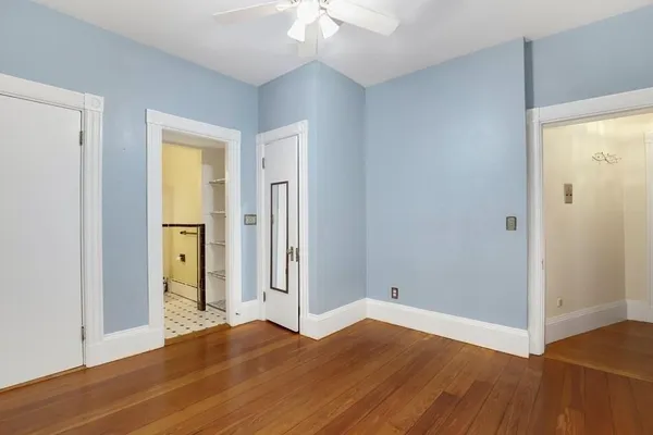 a view of empty room with wooden floor and fan
