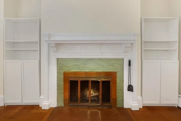 a view of an empty room with wooden floor and a fireplace