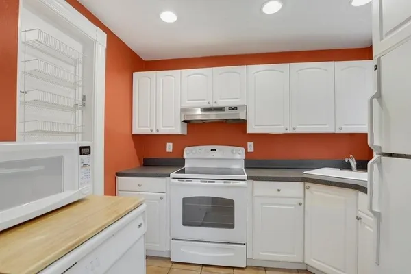 a kitchen with granite countertop white cabinets and white appliances
