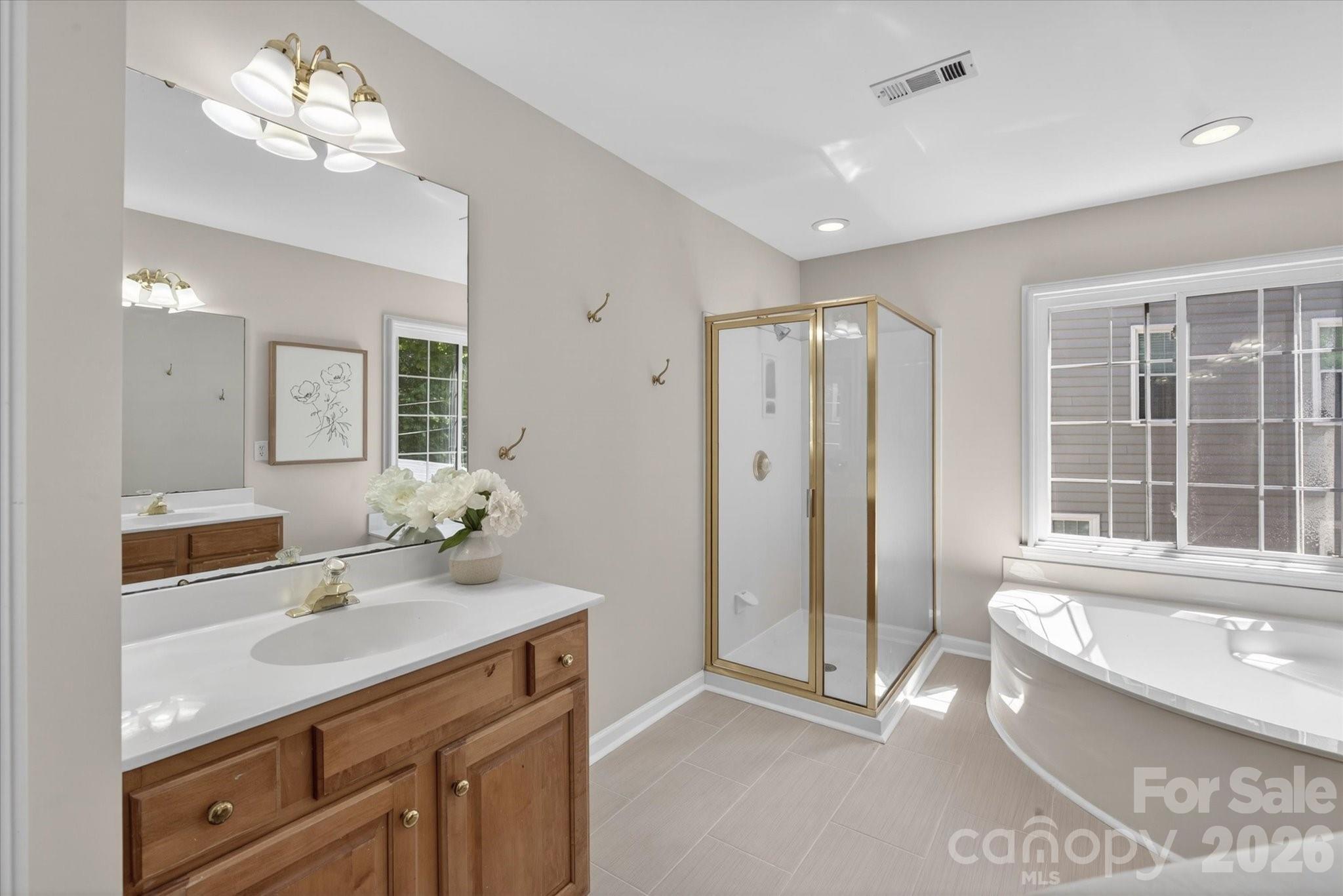 8528 Headford Road Charlotte, NC 28277 - Photo 20 of 34 a spacious bathroom with a double vanity sink a large mirror and a bathtub